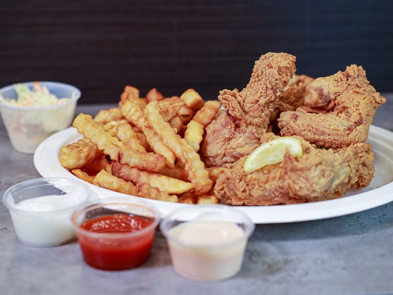 A plate of golden broasted chicken and fries with dipping sauces